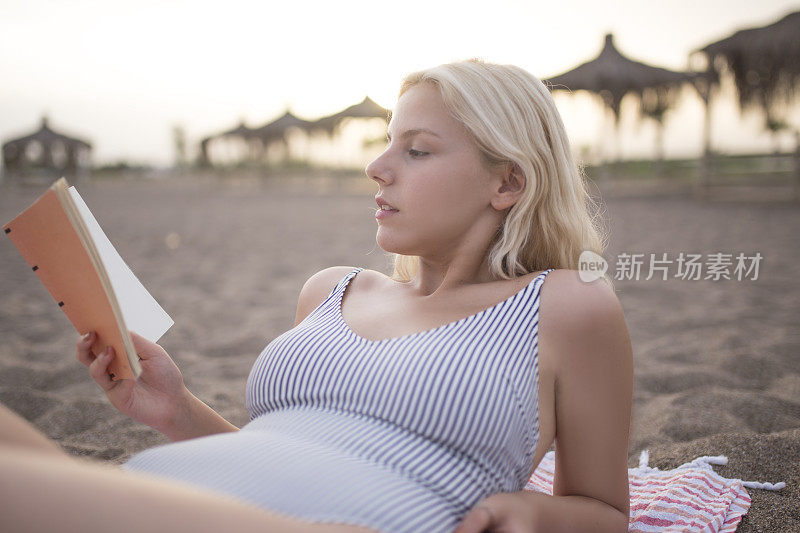 一个金发女人在海滩上看书