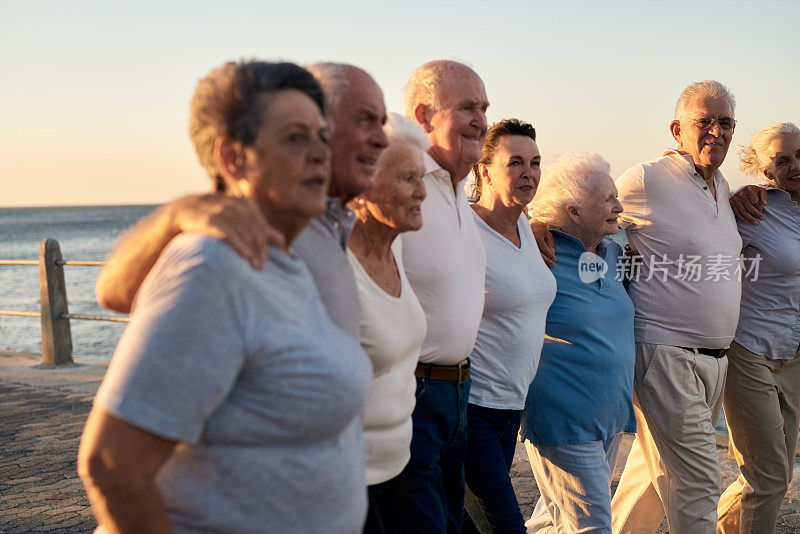 一群微笑的老人一起在海边散步