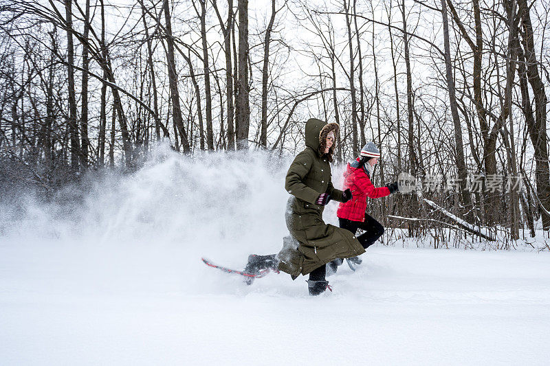 两个女人在冬天穿雪鞋和在森林里赛跑