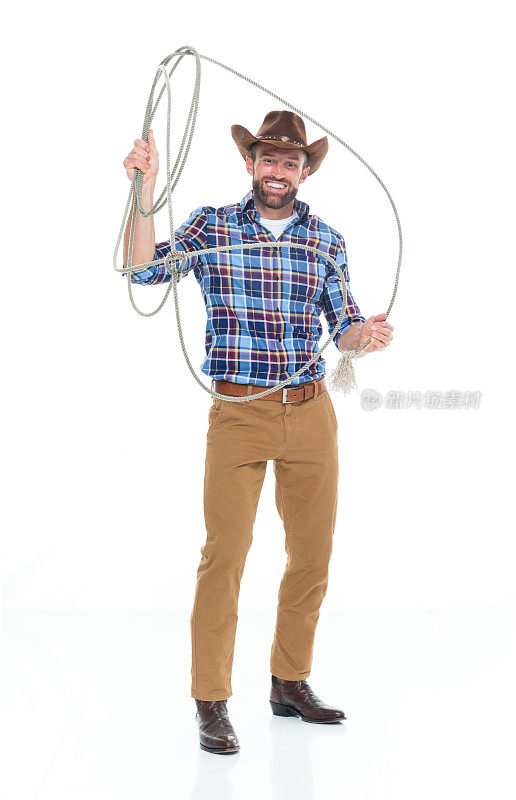 白人年轻男性牛仔戴着帽子，手持套索，用绳子站在白色背景前