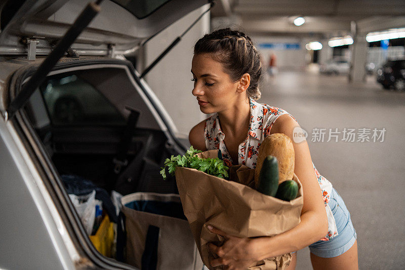 在汽车后备箱里装杂货的漂亮年轻女人