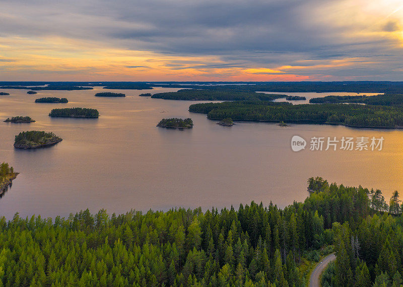 鸟瞰图上的小岛上蓝色的湖Saimaa。景观与无人机。在多云的夏日日落上，可以俯瞰蓝色的湖泊、岛屿和绿色的森林。芬兰的湖泊景观。