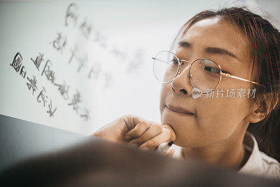 一位亚洲华人女性用她的马克笔在白板上写字