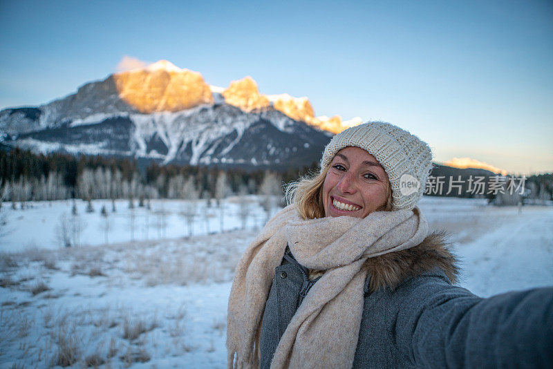 年轻女子在冬天与雪山景观自拍;人们在寒假里玩得很开心