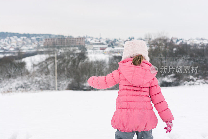 小女孩在雪地里奔跑的背影。