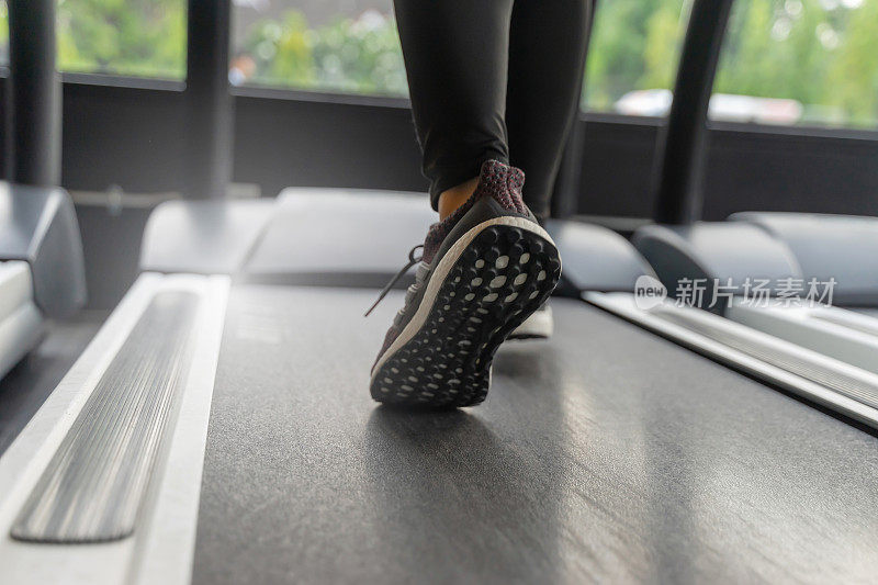 运行。运动跑步女脚跑步机在健身中心或健身俱乐部的阳光效果，有氧，健康的生活方式，运动健身，锻炼，运动训练的概念