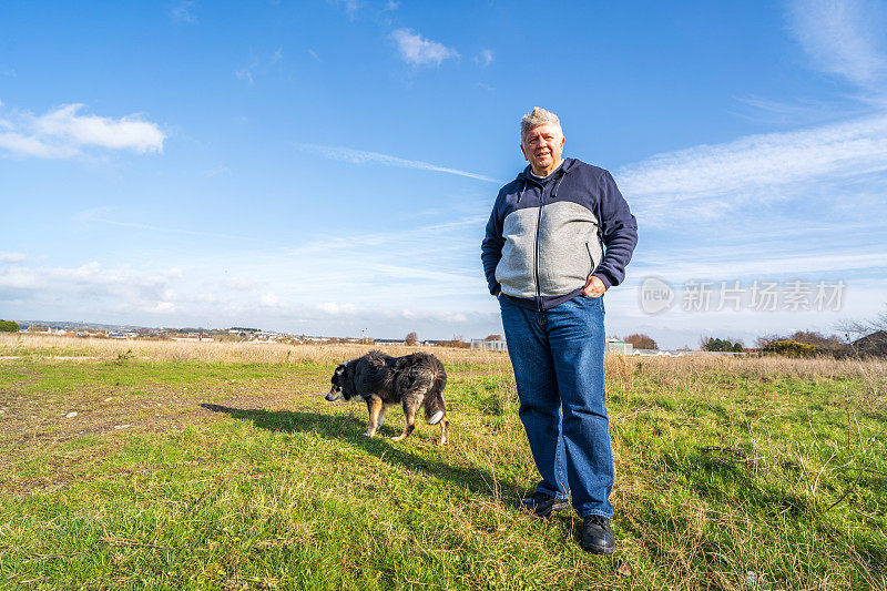 一名男子和边境牧羊犬在草原上散步