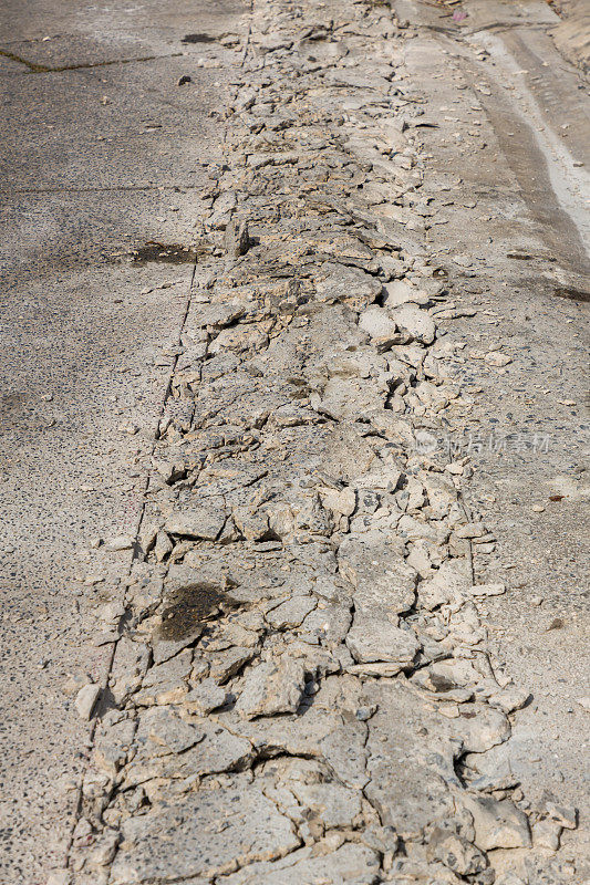 破碎的道路裂缝纹理。施工后用手提钻钻表面。挖掘机钻孔时混凝土破碎。这条路被挖掘和钻探以形成排水沟。