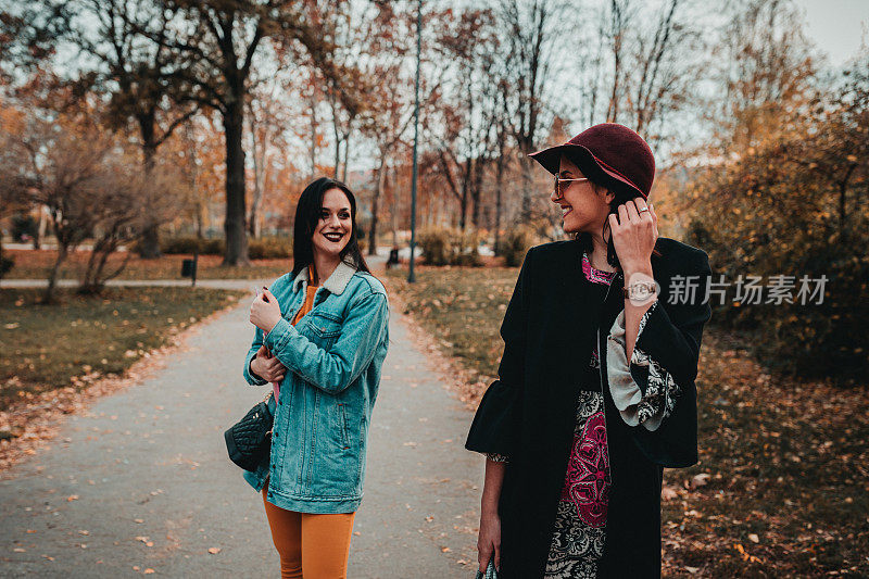 两个年轻女人在一个阳光明媚的日子里在公园里散步