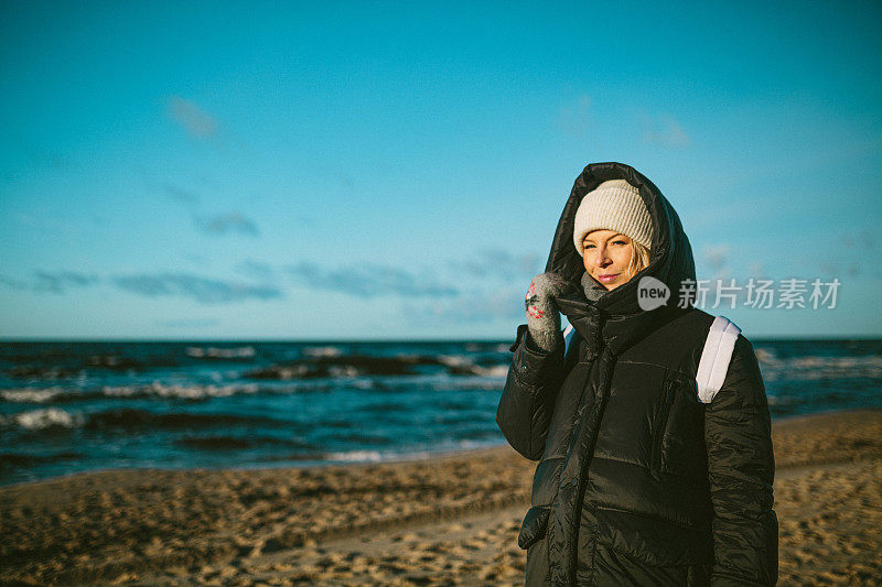 在一个寒冷的刮风的日子，一个年轻女子在海滩上。