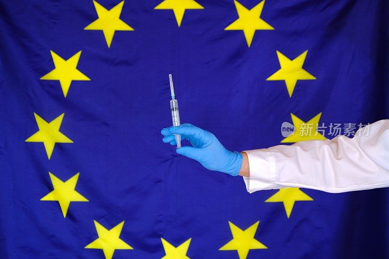 欧洲联盟病毒疾病的疫苗接种和检测。病毒疫苗。欧洲的冠状病毒治疗。医生的手和注射器在欧洲国旗的背景。