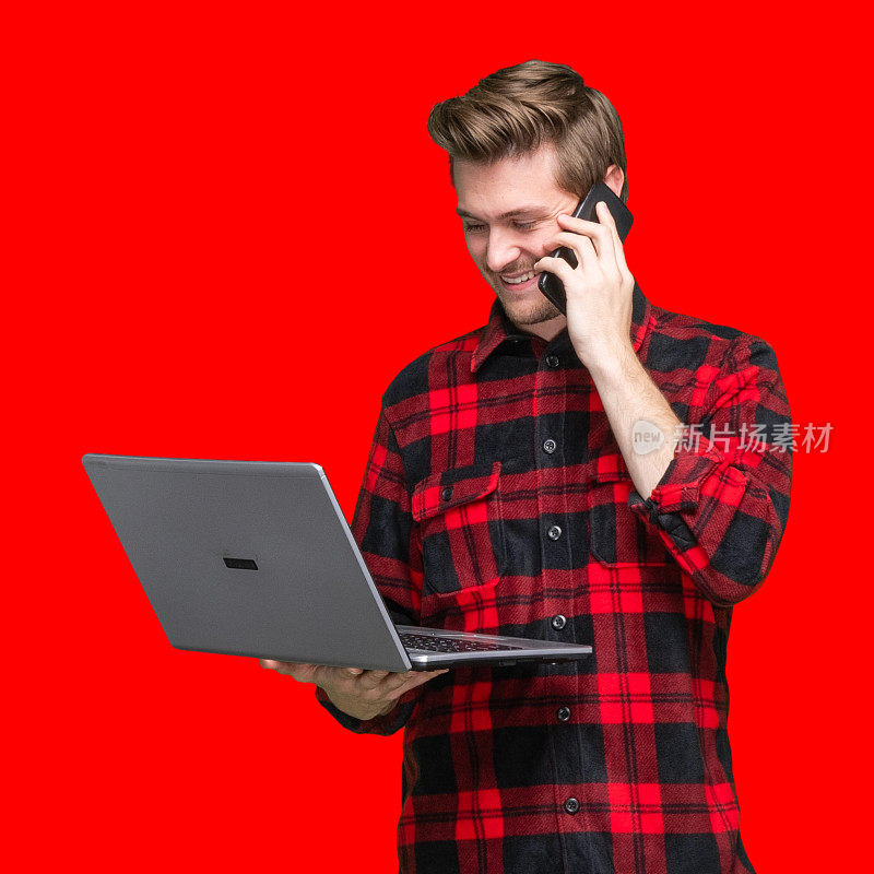 白人年轻男性站在有色背景前穿着衬衫，使用笔记本电脑