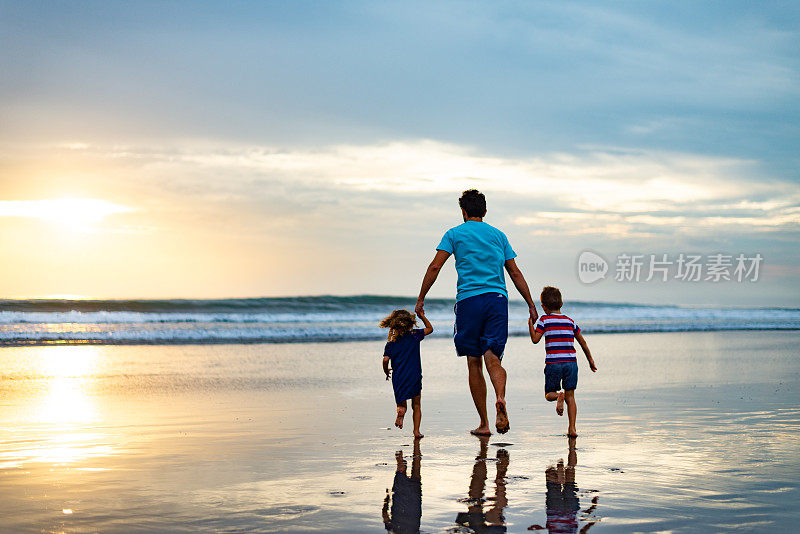 黄昏时分，单身父亲和孩子们在海滩上奔跑的背影