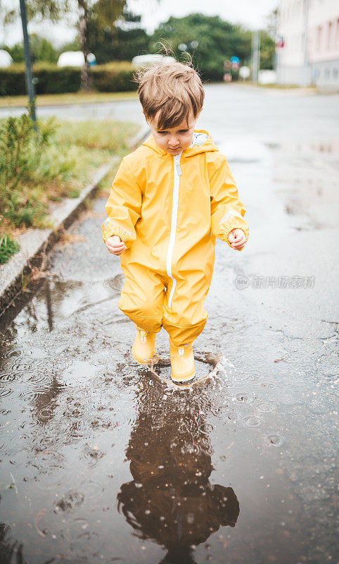 小男孩在雨中玩耍，跳进水里画画