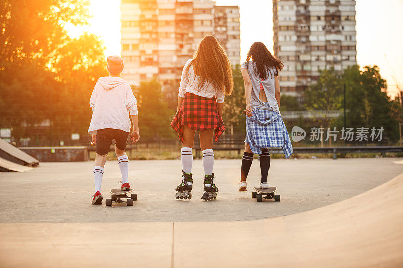 后视图三个十几岁的女孩在一起在滑板公园散步的乐趣