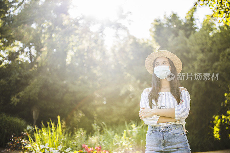 在冠状病毒大流行期间，戴着防护面罩的美丽女子在大自然中度过时光