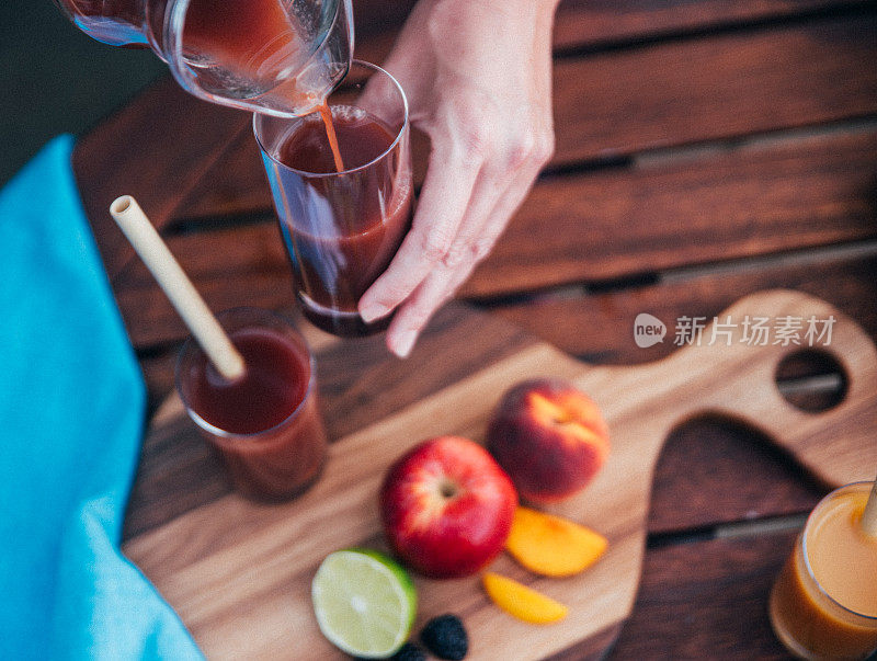 一位女士将维他命鸡尾酒中的冰沙倒入玻璃杯中