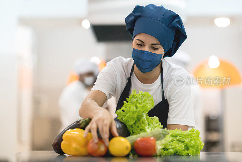 在餐厅工作的厨师戴着口罩挑选食材