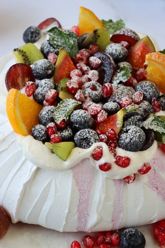 大理石蛋糕架上，大理石效果的背景，聚焦前景，用新鲜的水果，包括橙子，石榴籽，蓝莓，葡萄，猕猴桃和无花果撒上糖霜