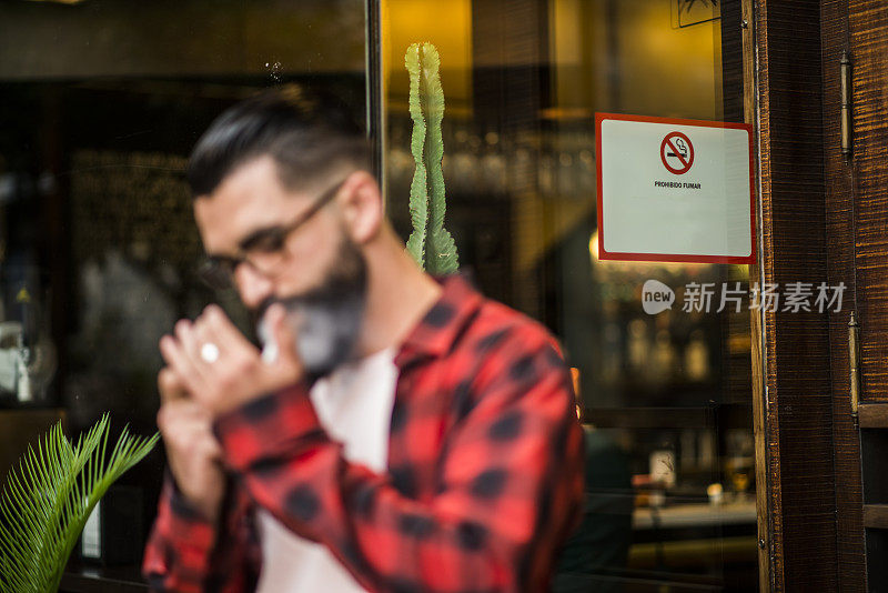 模糊的潮人附近的街道上不吸烟的广告，是禁止在室内