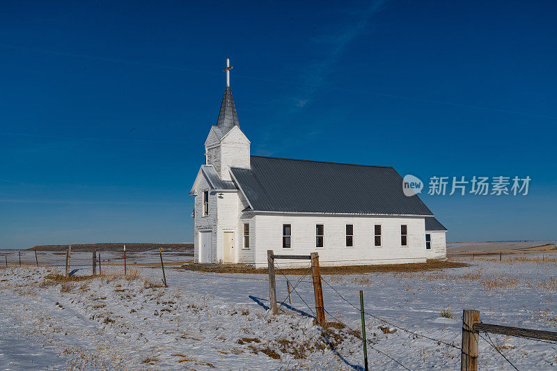 旧的废弃的教堂在白雪覆盖的小山和白雪覆盖的道路