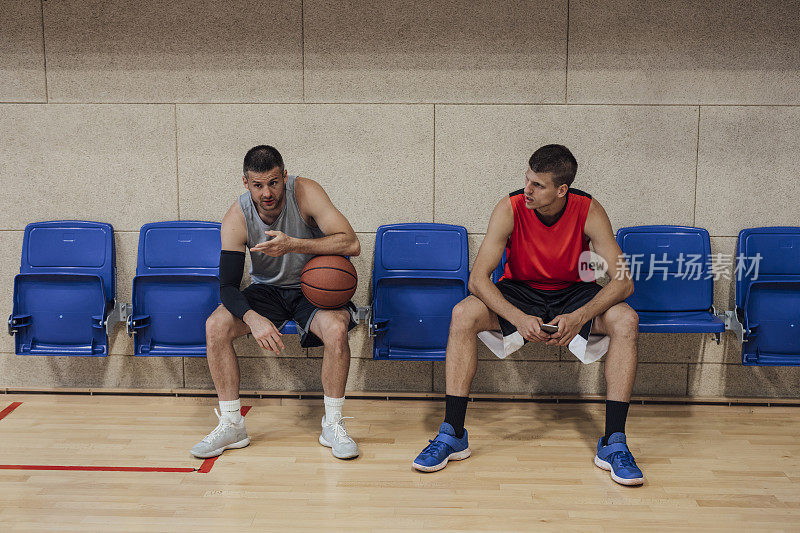 两个篮球运动员坐在球场边聊天