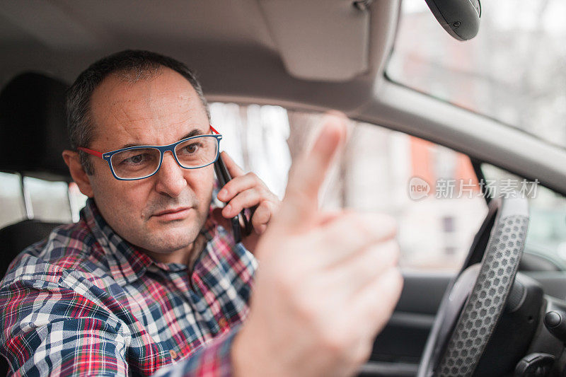 一个愤怒的男人坐在车里打电话