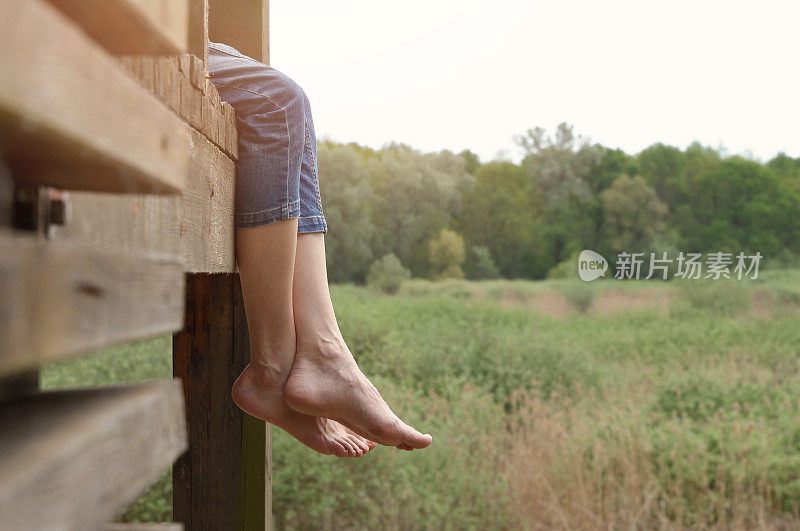 光脚女人坐在木码头上。缓解腿部疲劳。预防静脉曲张的理念