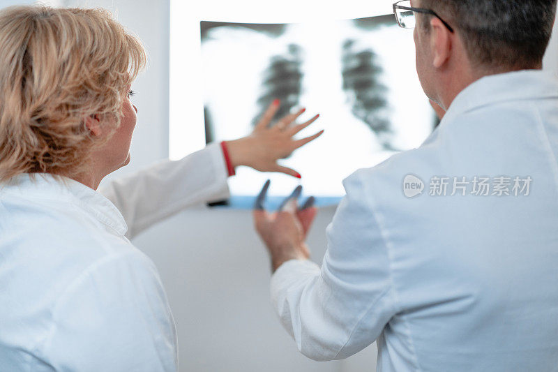 女放射科医生在看肺部x光片，和她的同事商量