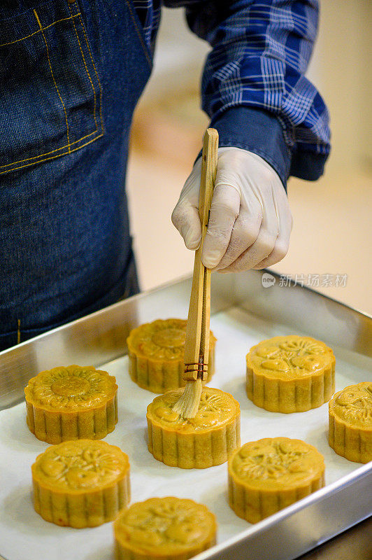 面包师在烤盘上用鸡蛋面团画自制月饼