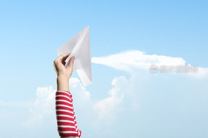 女孩手中拿着纸飞机，准备以蓝天为背景起飞