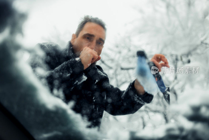 冬季开车。冬天的一天，这个人正在擦车窗上的雪。冬季，一名白人男子正在用刷子把车里的雪清除掉。