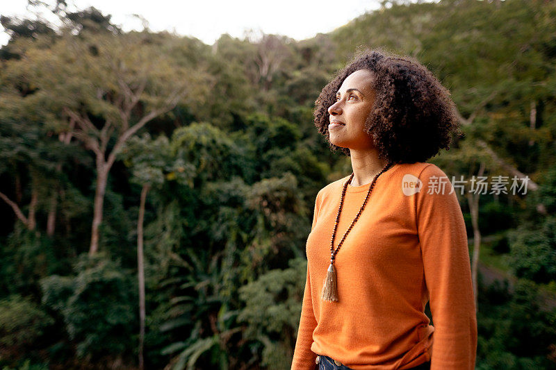 微笑的女人看着窗外森林的风景