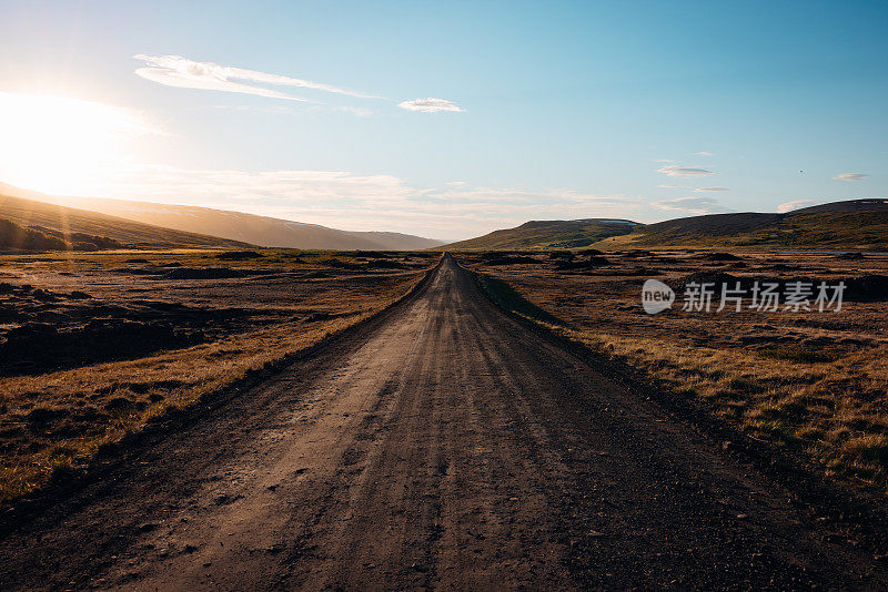 冰岛日落之光中的砾石乡村道路中间