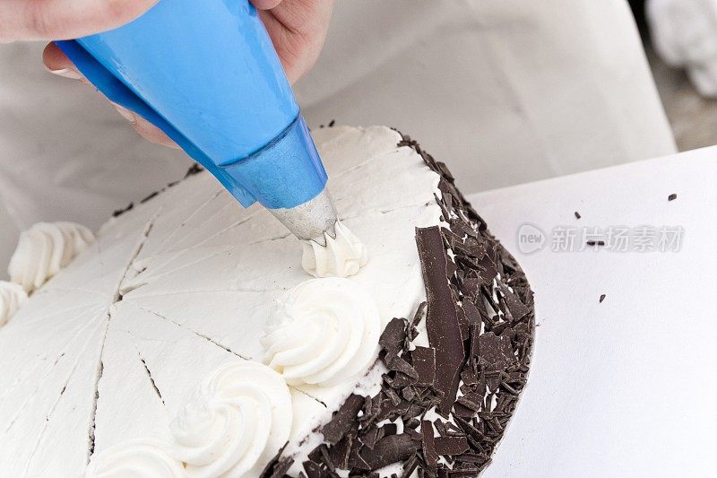 糕点师用奶油漩涡巧妙地装饰着奶油蛋糕