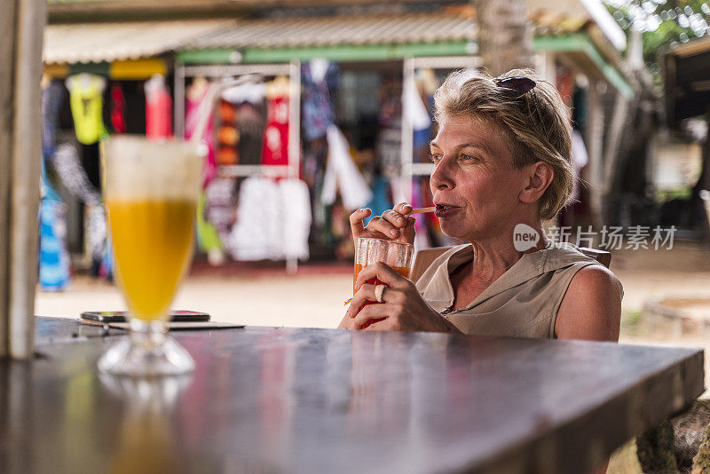 一个50岁的欧洲女游客在沙滩上的露天餐厅里