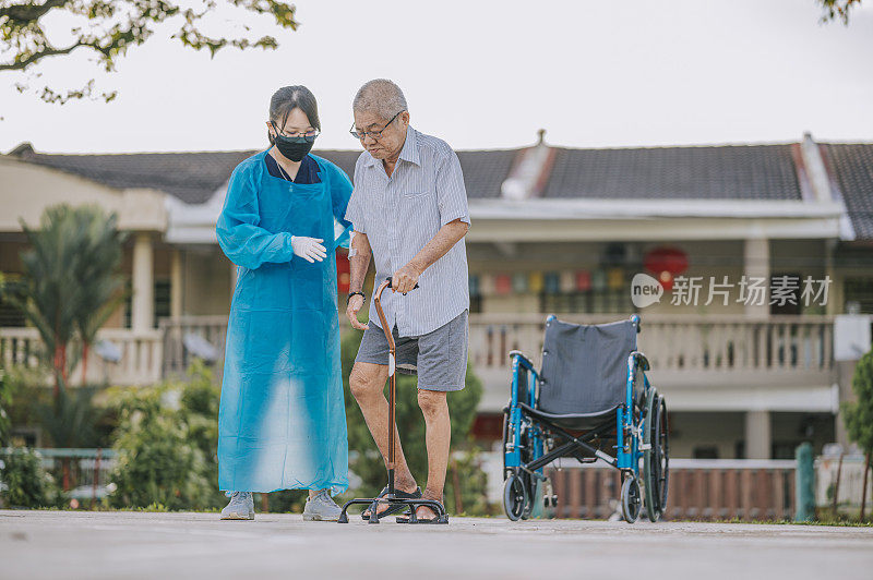 亚裔中国女性理疗师帮助老人拄着拐杖在公园散步