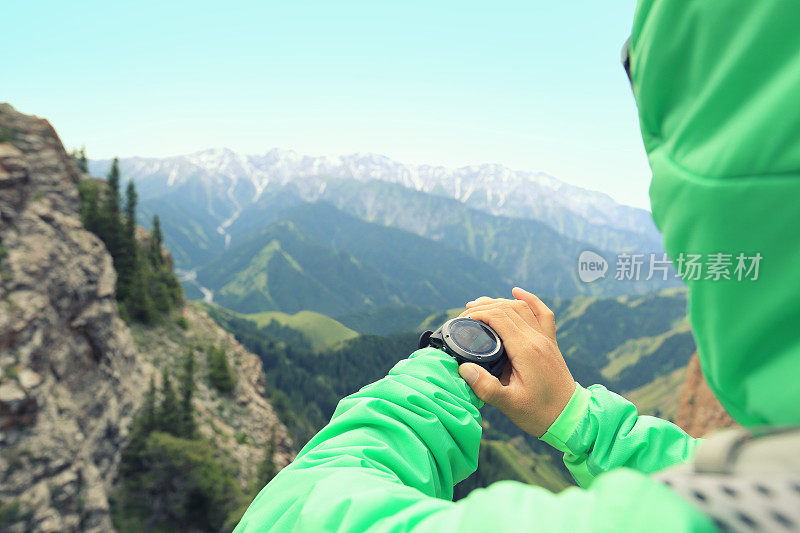 登山者在山顶检查运动手表上的高度计