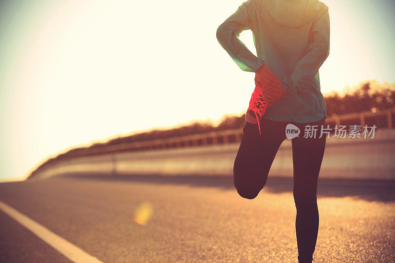 年轻的女健身运动员在跑步前伸展双腿