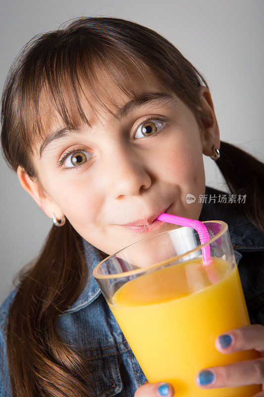 可爱的小女孩喝着橙汁;孤立在白色