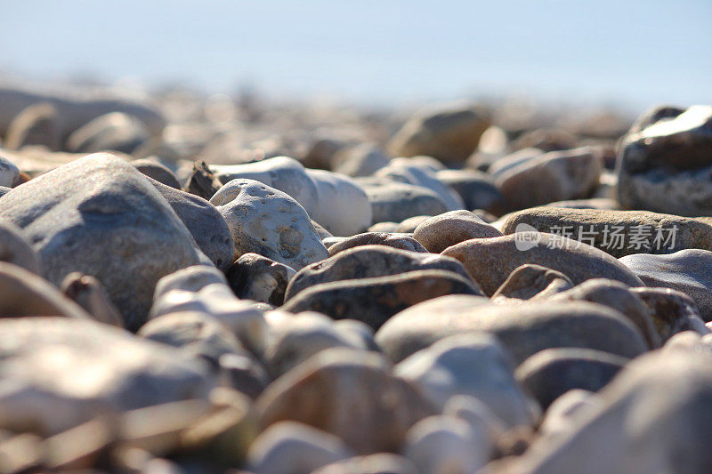 不规则的灰棕色沙滩卵石和沙子的图像，海岸侵蚀