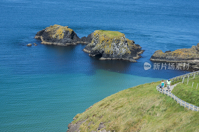 夏日，两个人在北爱尔兰安特里姆郡的海边散步