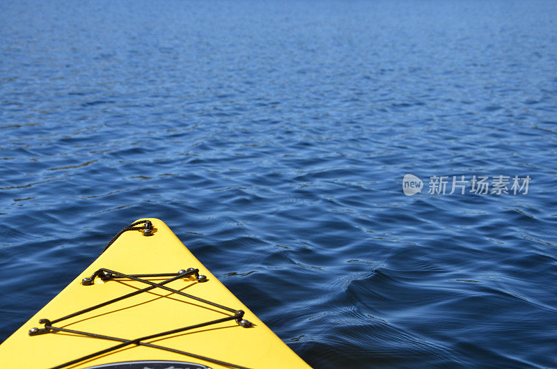 黄色皮划艇在蓝色湖划桨的观点