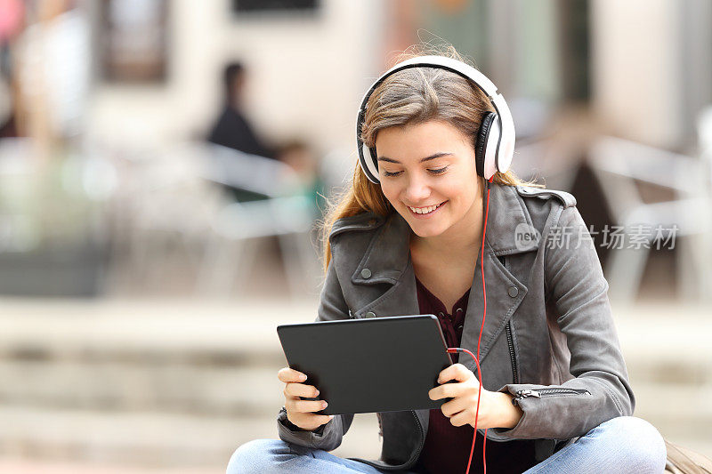 一个女孩带着平板电脑和耳机在网上学习