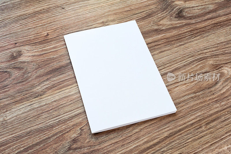 一本小册子的空白页放在一张木桌上。