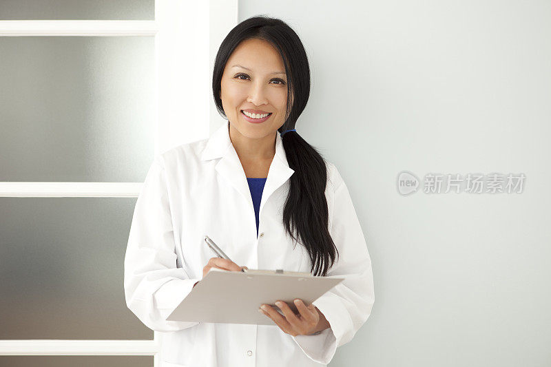 自信的亚洲女医生在写字板上做笔记
