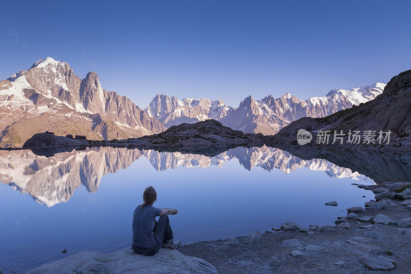 女人看着阿尔卑斯山脉和美丽的倒影在湖中