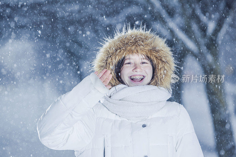 雪下穿着白色夹克的漂亮少女