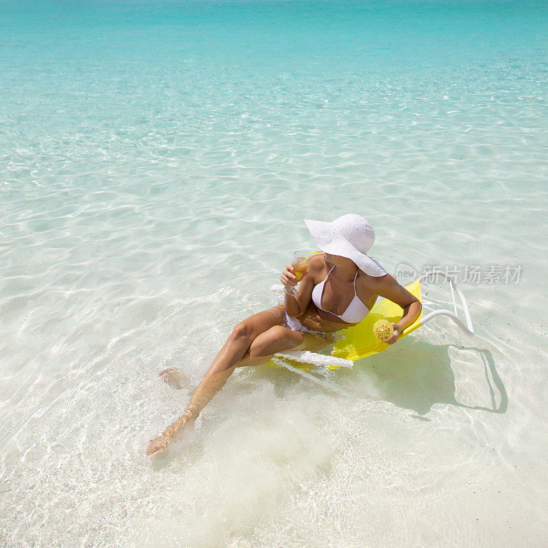 性感的女人享受一个热带鸡尾酒在加勒比海滩上