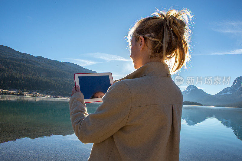年轻女子用数码平板电脑拍摄壮观的风景